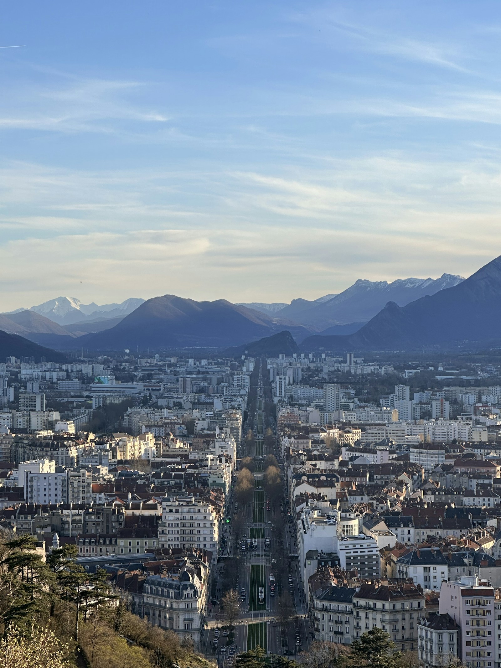 Vue de Grenoble et des montagnes sous un ciel bleu.